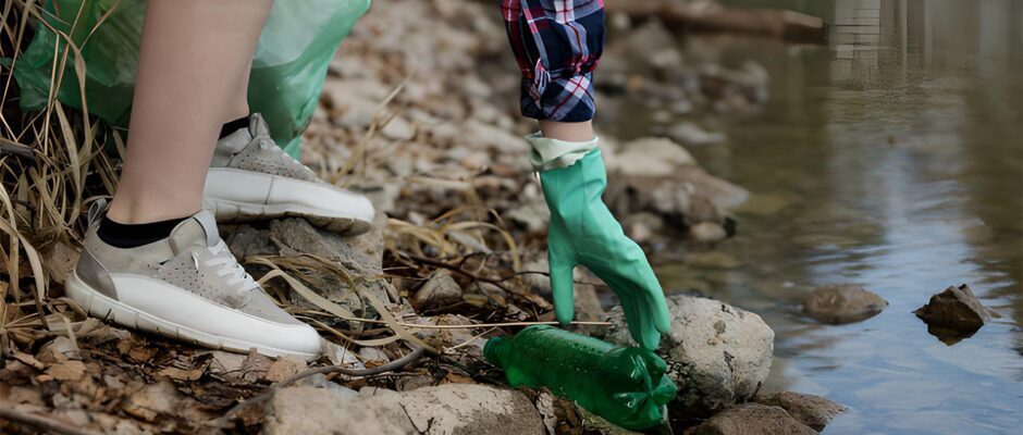 Persona con guante de caucho recoge botellas de plástico en limpieza de un río