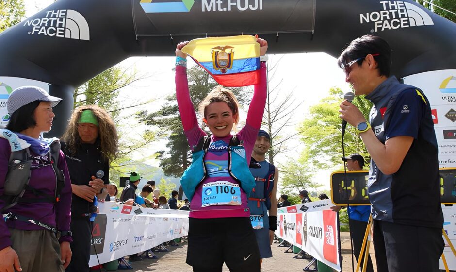Mujer sostiene la bandera de Ecuador con felicidad en la meta de una carrera con logos de The North Face