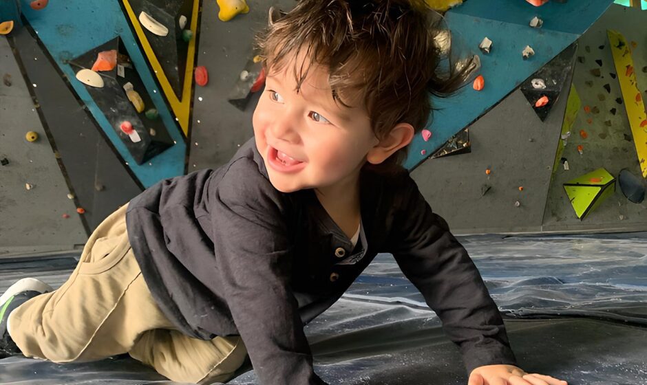 Infante jugando en colchoneta de una pared, de espalda