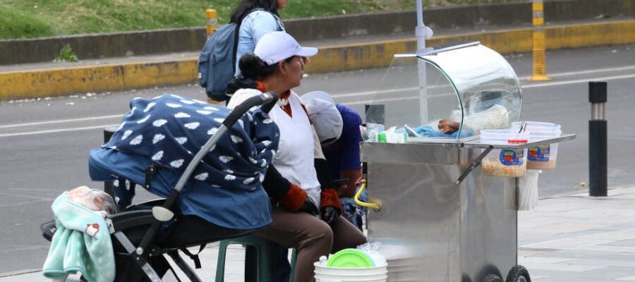 Vendedora de comida en la calle con coche de bebé a un lado de su puesto