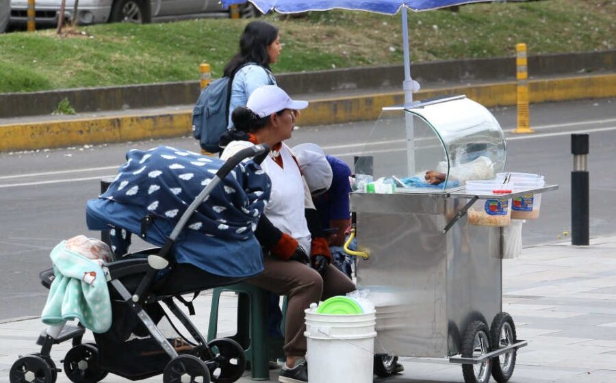 Vendedora de comida en la calle con coche de bebé a un lado de su puesto