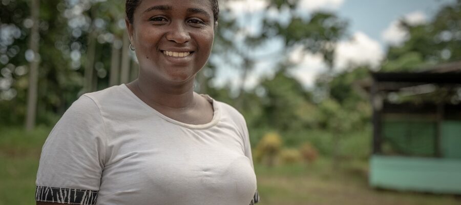 Mujer joven afrodescendiente sonriendo con un fondo de árboles